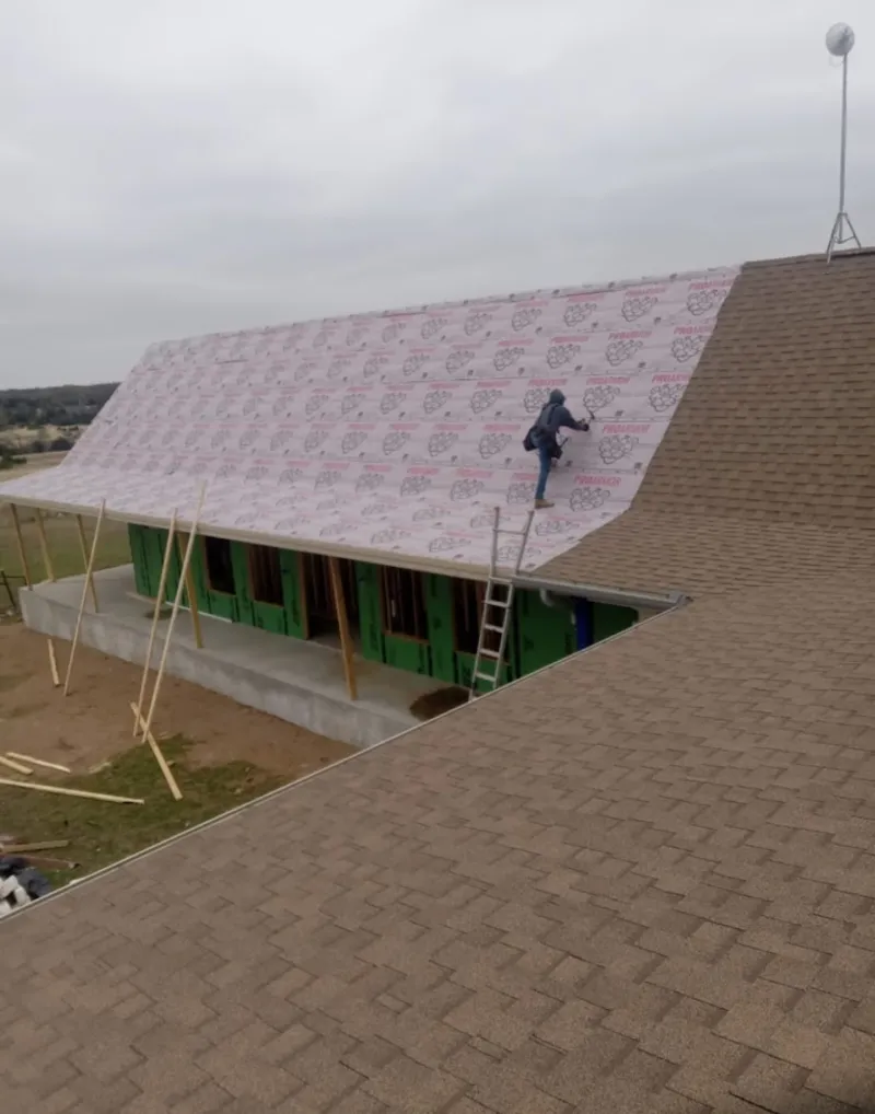 Worker preparing underlayment for a metal roof installation in Marietta